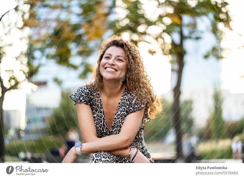 Portrait of a smiling young woman with curly hair in the city young adult street outside confidence enjoy laughing fun natural one person portrait expression