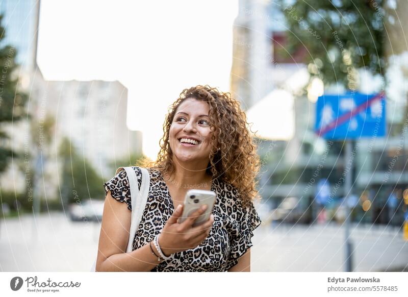 Portrait of a smiling young woman using mobile phone in the city young adult street outside confidence enjoy laughing fun natural one person portrait expression