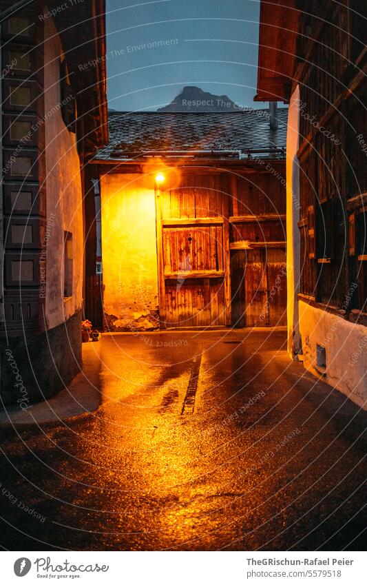 Mountain village at dusk with lights - Sent Village Church Moody Dark Dusk clearer roofs mountains sentinel Lower Engadine Switzerland Alley reflection Wet Barn