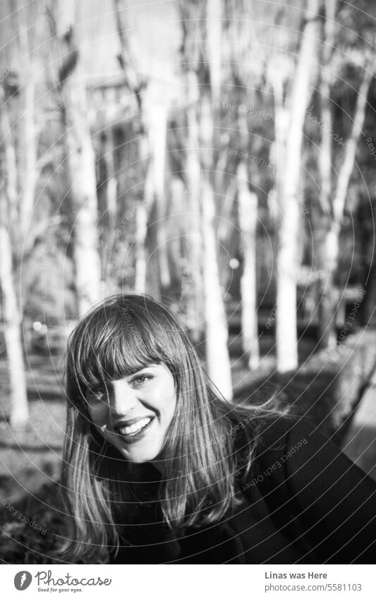 A stunning woman is smiling broadly. This is a joyful season for her. Autumn. A photo captures a beautiful girl's modeling session in black and white, conveying genuine feelings of happiness.