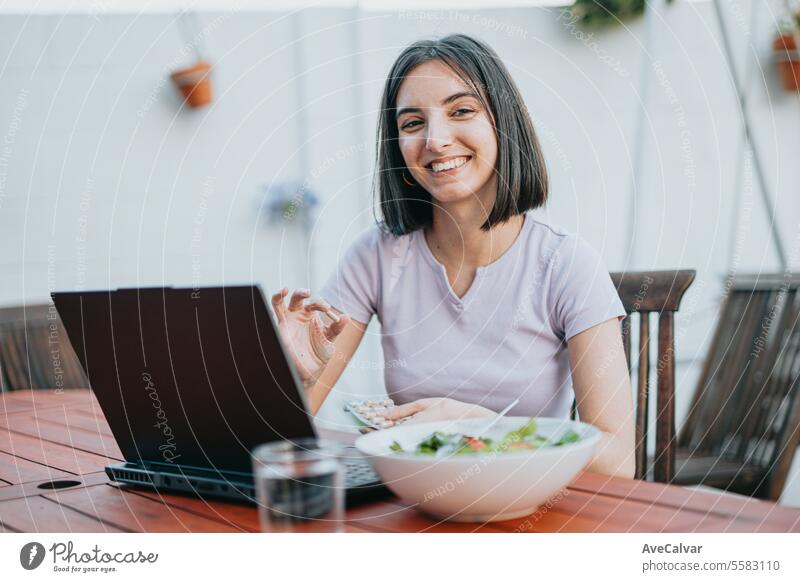 Woman sitting at home and taking painkillers pills while working on laptop, freelancer concept. supplement woman happy vitamin healthy notebook student japanese