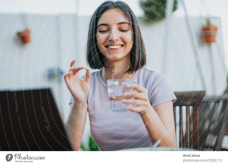 Woman sitting at home and taking painkillers pills while working on laptop, freelancer concept. supplement woman happy vitamin healthy student using