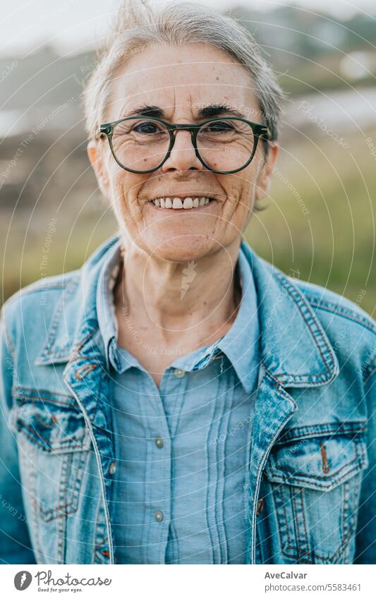 Smiling adult woman with short gray hair visiting a beach, connecting with nature taking a walk. mental health retirement senior portrait happy caucasian female