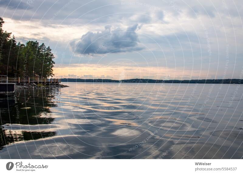 The surface of the lake in the evening light is in motion, there are beautiful clouds in the sky Lake Water Surface Evening Sunset Light Sky reflections