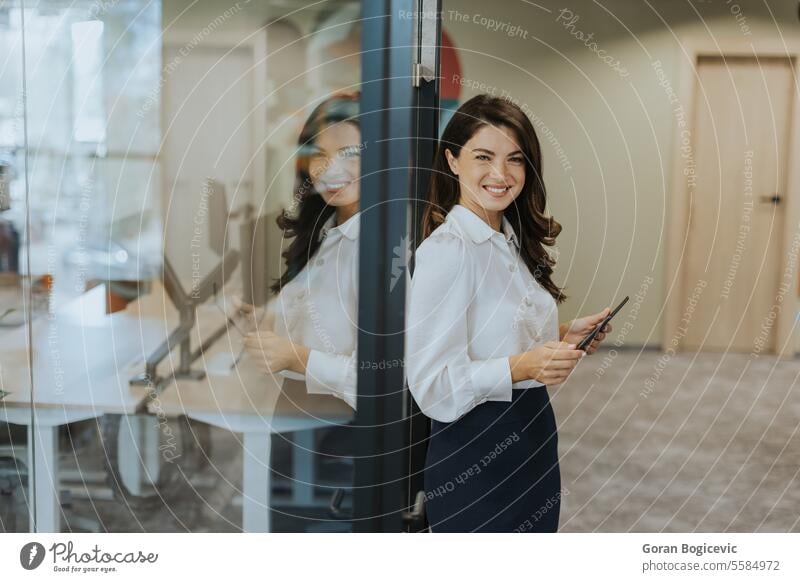 Young woman with digital tablet standing in the modern office young businesswoman female attractive technology portrait wireless occupation confident