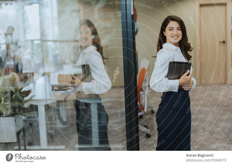 Young woman with digital tablet walking in the modern office hallway adult attractive beautiful business businesswoman casual cheerful communication company