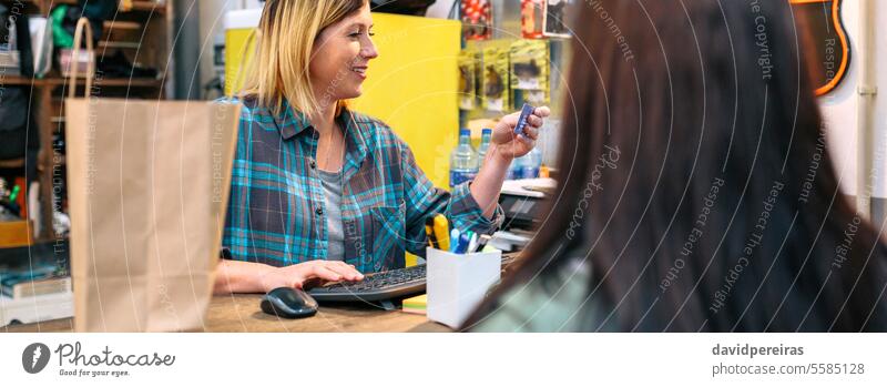 Banner of woman shop assistant registering client data in store terminal to make invoice of purchase female happy checking database computer bill local panorama