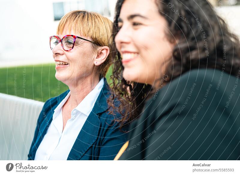 Businesspeople using the smartphones sitting on a bench in the city. Sharing time co workers rest. businesswoman office colleague person happy women lifestyle