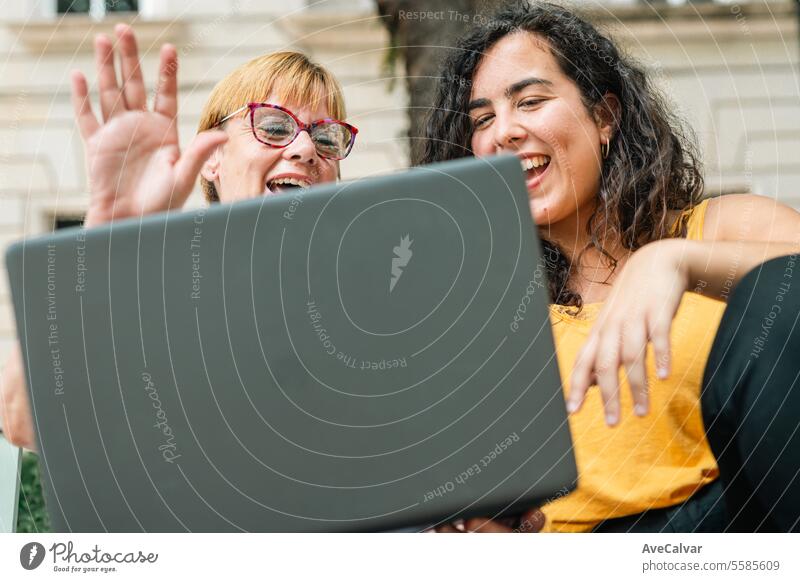 video call with relatives while using laptop with her daughter sitting in a bench at the street office colleague person female computer young women technology