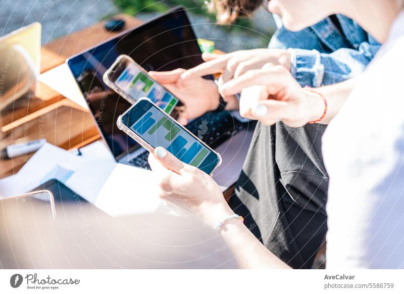 Detail of hands texting with mobile phones green and blue with computers behind. Messaging apps. women students studying happy bonding touch typing chat