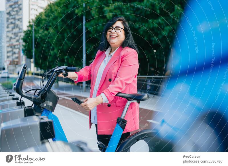 Excited business woman renting a bicycle from public transportation so she can tour the city freely. biking female women street person young lifestyle senior