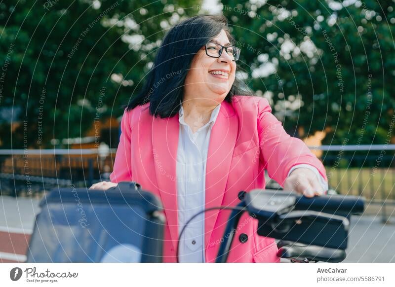 Excited business woman renting a bicycle from public transportation so she can tour the city freely. person women happy portrait smile female adult senior