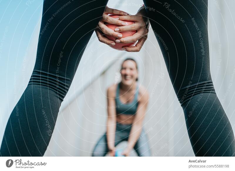 Two fit women doing sports together, using a medicine ball to tone their body. Urban scene. female fitness outdoor urban friends training lifestyle person