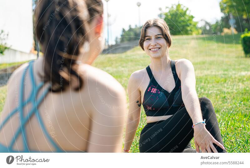 University friends resting on the campus grass while stretching to avoid injury after training. female sport healthy fitness exercise person young lifestyle