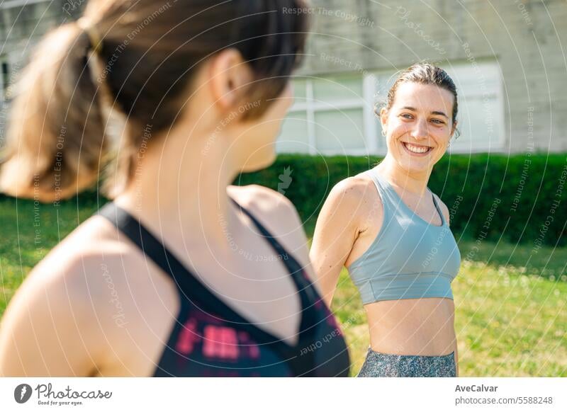 Two friends having a good time while warming up before doing the training provided by a professional healthy female fitness women young sport person athletic