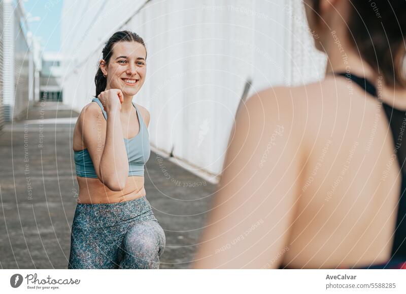 Young woman trainer teaching the different exercises to a student while they exercise with a smile. female body lifestyle fitness person young adult sport