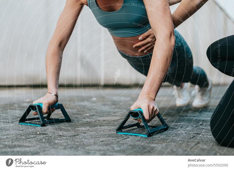 Two young girls helping each other do push-ups,being careful with their posture to strengthen muscle sport exercising fitness outdoor urban friends training gym