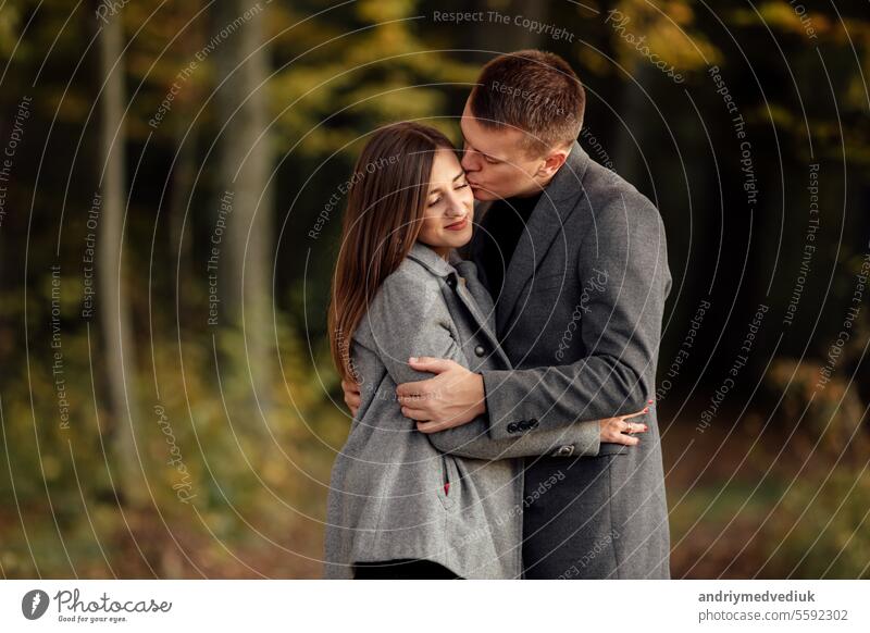 Beautiful young couple man and woman in love. Boyfriend and girlfriend hugging together in park on autumn sunny day. Tenderness and happiness. romantic