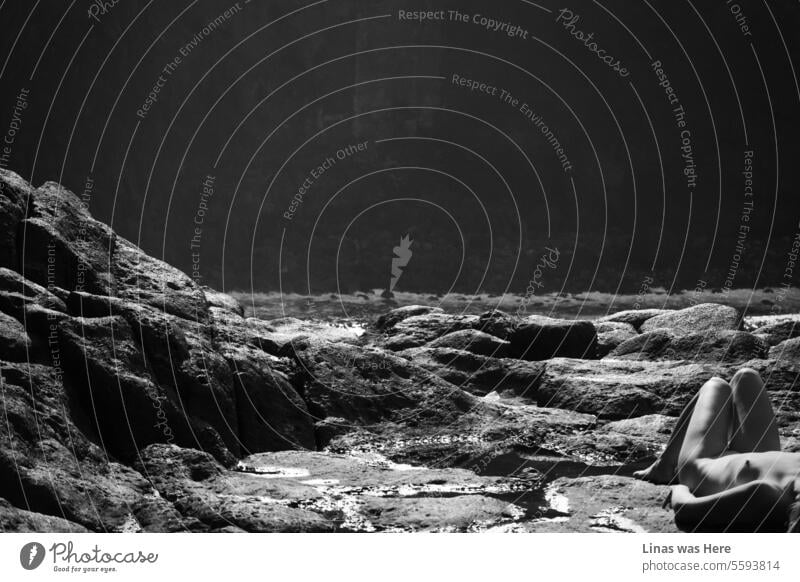 A gorgeous naked girl is sunbathing alone. Surrounded by this rough terrain with rocks and mountains everywhere around her. It’s a wild nature and volcanic view with a beautiful nude woman.