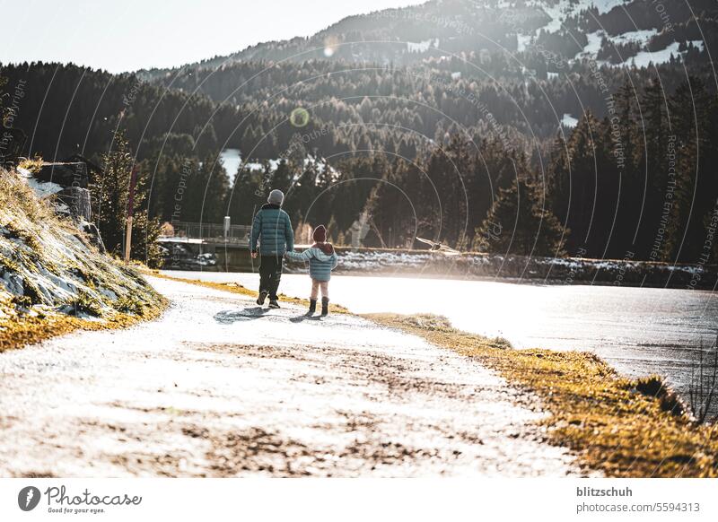 Two children walk together along the shore of a mountain lake on a beautiful November afternoon Brother Sister Brothers and sisters Walking Hiking Lake Girl