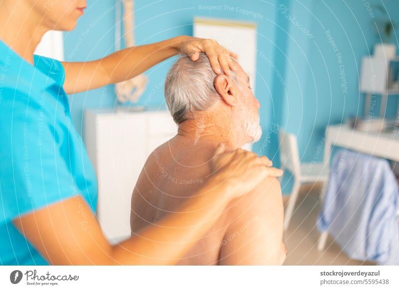 A female physiotherapist performs stretches on the neck of her patient, an elderly man, to aid in his rehabilitation and wellbeing treatment manual therapy