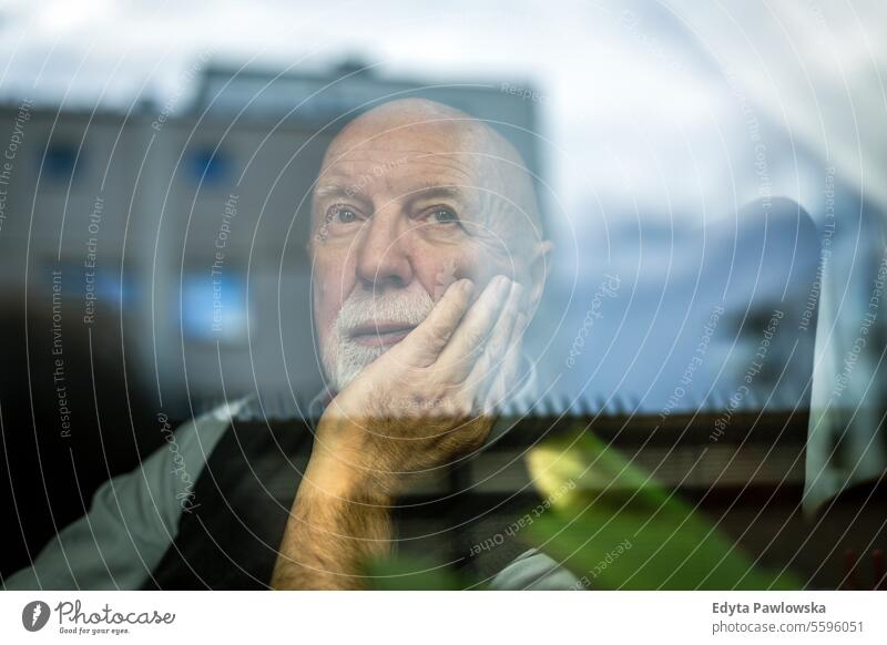 Portrait of thoughtful senior man looking through window real people senior adult mature male Caucasian elderly home house old aging domestic life grandfather