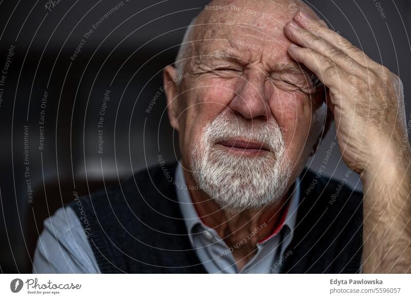 Portrait of a senior man suffering from a headache real people senior adult mature male Caucasian elderly home house old aging domestic life grandfather