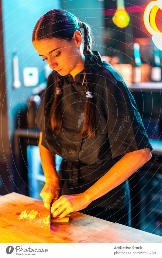 Confident skilled cook standing at counter while cutting and preparing seafood at sushi bar woman chef knife confident meal bistro illuminated prepare dinner