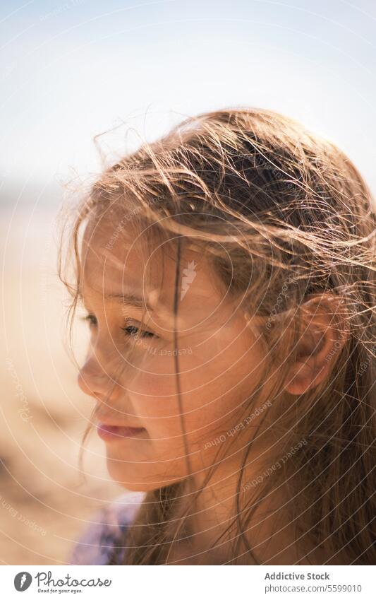 Sunlit contemplation girl profile sunlight hair close-up strand serene thoughtful expression face youth child gaze warmth shadow side beauty innocence day