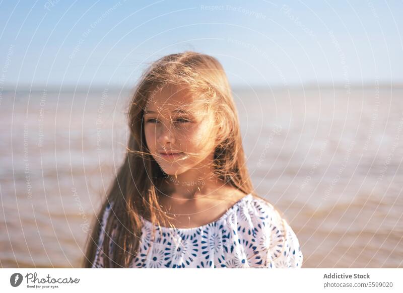 Skyward gaze girl portrait hair wind blue pattern top shoulder sky clear close-up face eye serene youth child innocence summer outdoor sunlight peaceful