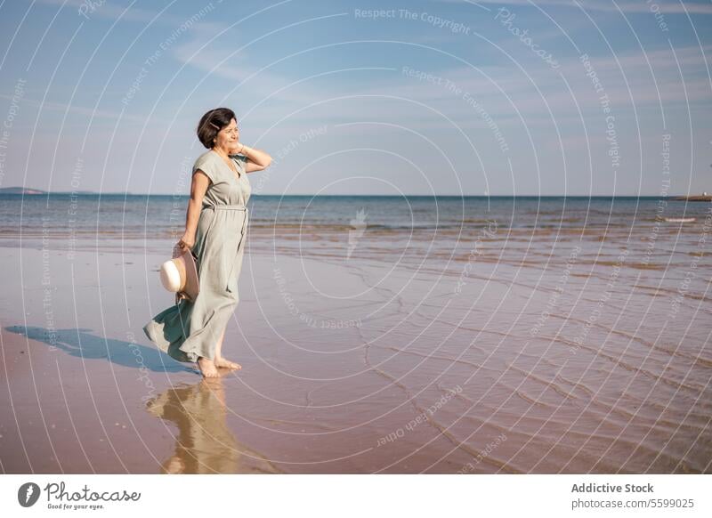 Woman gazing at sea horizon woman beach dress sun hat sand reflection sky gaze summer coast water wave shield hand stand serene outdoors sunlight tranquility