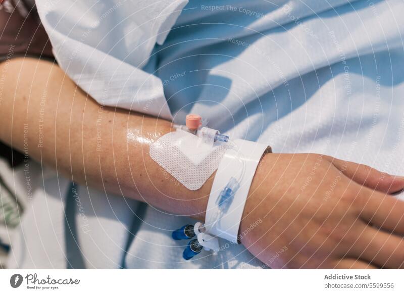 Close up view of the hand of a patient in a hospital bed. intravenous medical medicine health treatment injection tube medication drug healthcare therapy