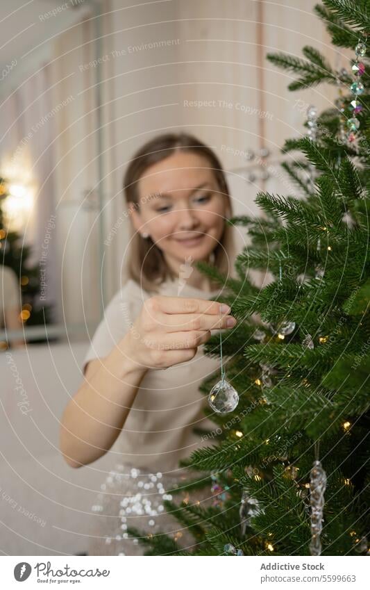 Woman decorating Christmas tree with festive joy woman christmas decoration tinsel silver holiday season happy cheerful room light tradition ornament celebrate