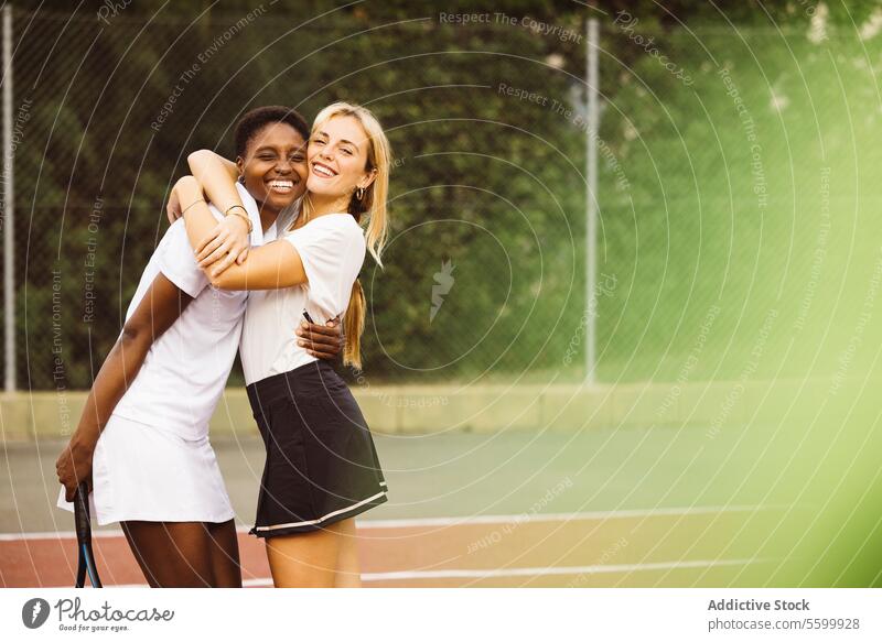 Portrait of two happy women in a tennis court active lifestyle activity amateur athlete ball beautiful beautiful women cheerful competition diversity enjoyment