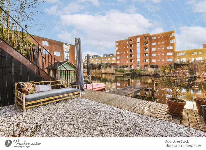 Deck with couch overlooking river and buildings sofa cushion view pier harbor flowerpot plant water sky structure window apartment residential district city