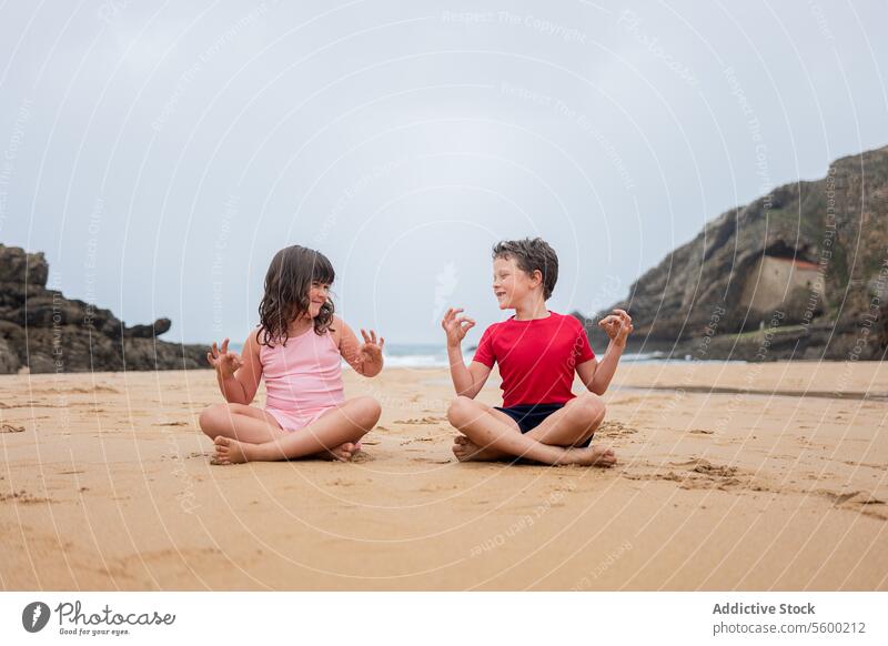 Playful Beach Day Conversation Between Two Children child beach conversation playful sitting sand overcast sky friend childhood joy leisure outdoor nature coast