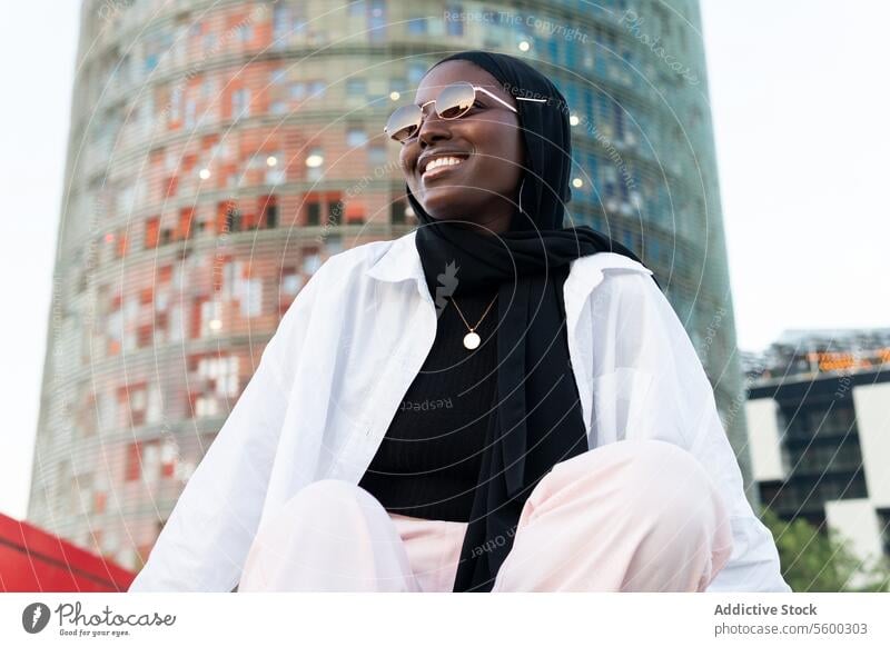 Stylish businesswoman in hijab and sunglasses in city black entrepreneur fashionable building from below stylish blur professional occupation manager confident