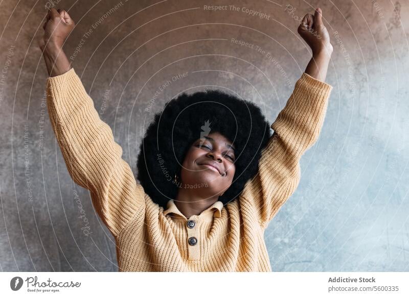 Smiling black woman stretching after waking up wake up home weekend awake relax comfort enjoy arms raised female african american morning afro eyes closed