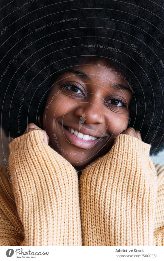 Black woman with her hands resting on her face looking at camera smile portrait cheerful afro appearance funny female black african american curly hair young