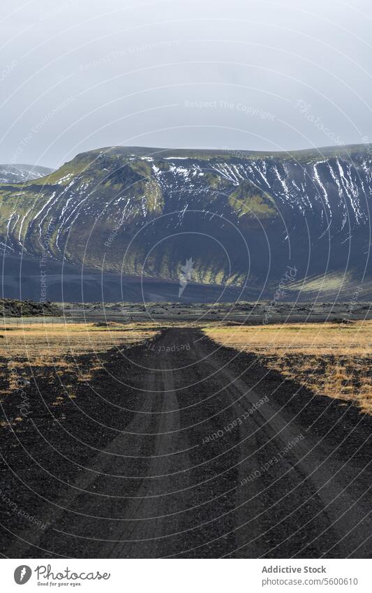 Remote gravel road leading to snowy mountain in Iceland iceland highland landscape remote solitude vastness serenity outdoor nature volcanic terrain travel