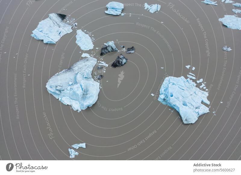 Ice fragments in glacial waters ice chunk boulder muddy meltwater Vatnajökull national park Iceland iceberg sediment silt brown blue natural arctic melting