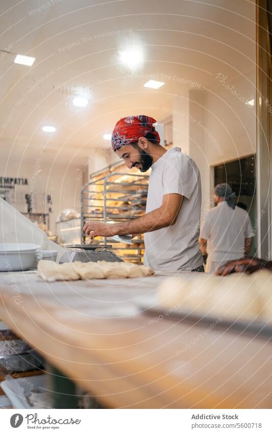 Arabic baker weighting dough with scale arabic scapula bread preparation bakery making happy smile flour raw table fresh cutter utensil pastry working kneading