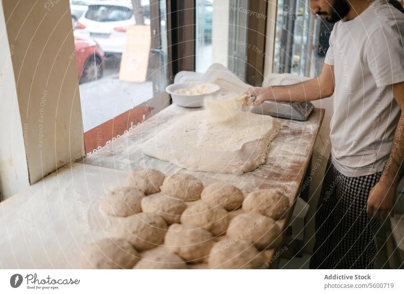 Baker pouring flour on the dough arabic baker bakery preparation bread fermentation yeast fresh oven senior pizza focaccia kitchen man male person board work