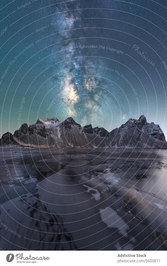 Celestial Glow over Frozen Lake at Night celestial glow frozen vista Milky Way ice patterns rugged mountain peaks contrast dark rocks starry sky awe-inspiring