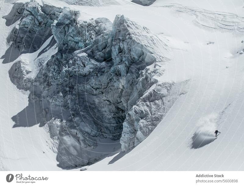 High angle of unrecognizable person skiing on snow mountain during vacation at Swiss Alps during sunny dayt skier enjoy winter covering swiss alps from above