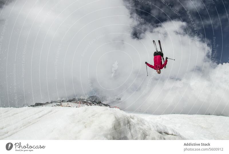 Anonymous carefree man skiing and jumping on snowy mountain while enjoying winter day at Swiss Alps skier active pole vacation adventure motion mid-air sky