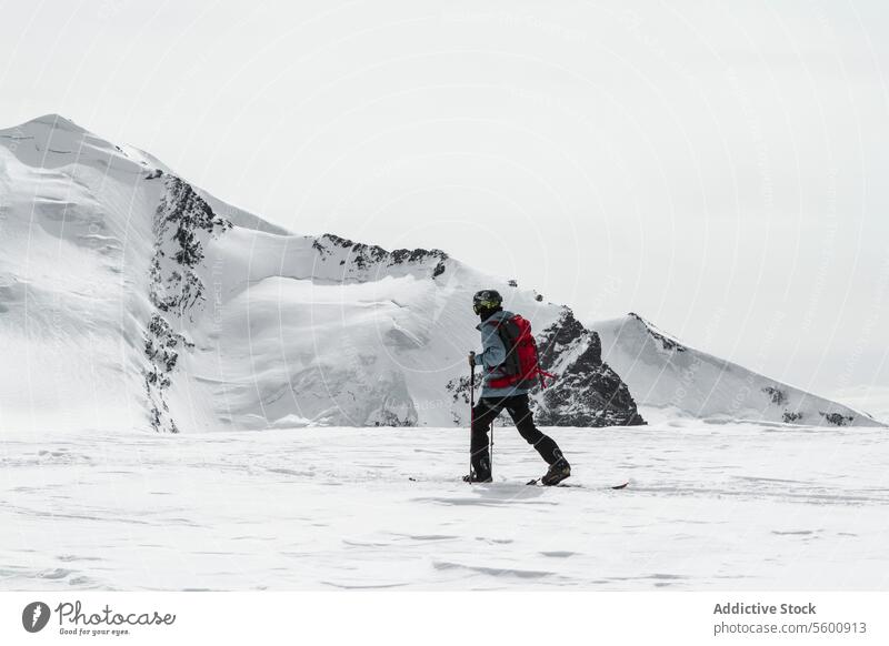 Full body of anonymous man skiing on snowy landscape on sunny day in winter at Swiss Alps skier pole warm clothes backpack ride white mountain hiker swiss alps