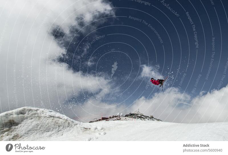 Anonymous carefree man skiing and jumping on snowy mountain while enjoying winter day at Swiss Alps skier active pole vacation adventure motion mid-air sky