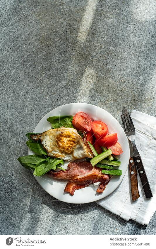 From above of healthy Breakfast Plate with Egg and Bacon breakfast plate vegetables tomato cucumber spinach fried egg bacon white crispy fresh leaves sliced