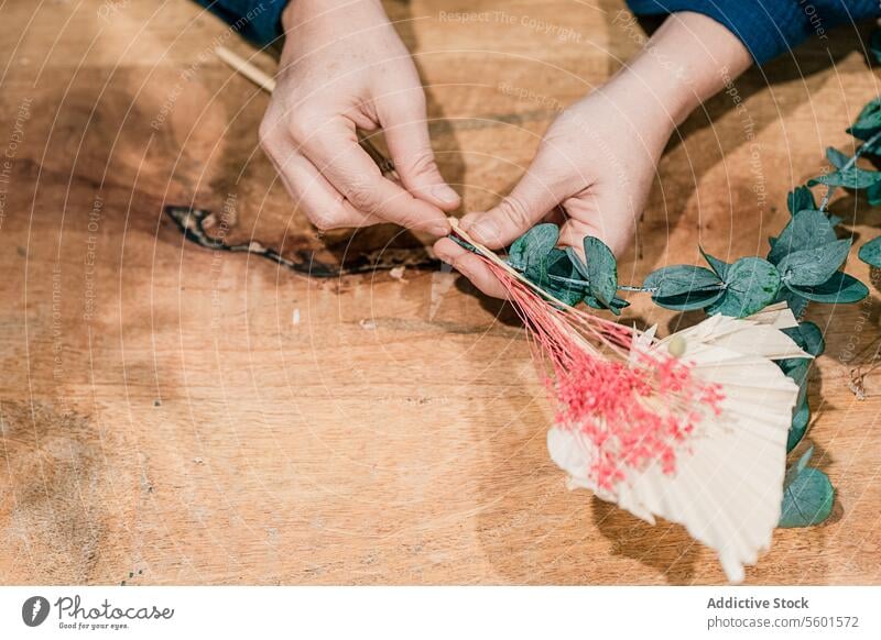 Anonymous hands creating a beautiful floral arrangement on wood crafting flowers table female close-up decoration hobby woman creativity design make foliage